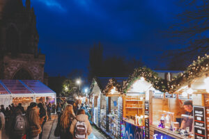 Crowds of people visiting the global street food chalets at Exeter Cathedral Christmas Market set on Cathedral Green.